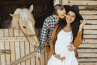 Man kissing the woman on cheek near stable