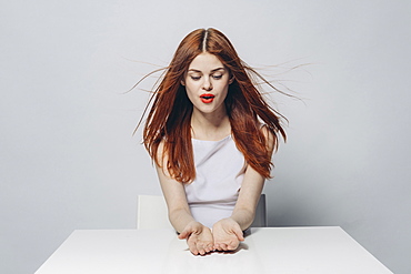 Hopeful Caucasian woman sitting at windy table