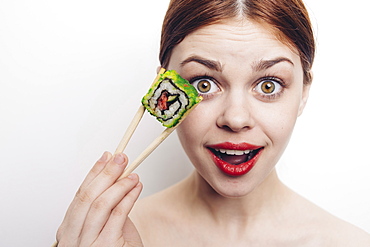 Caucasian woman holding sushi with chopsticks