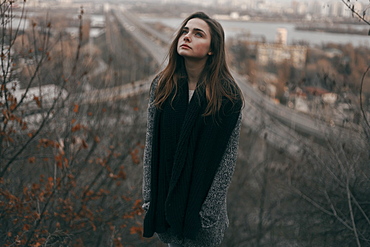 Portrait of pensive Caucasian woman standing on hill near freeway