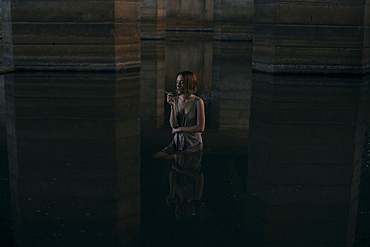 Caucasian woman standing waist deep in water smoking cigarette