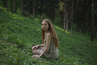 Serious Caucasian woman sitting on hill