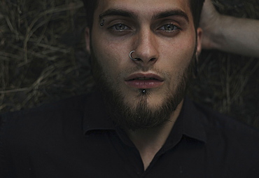 Serious Caucasian man with eyebrow and nose piercing