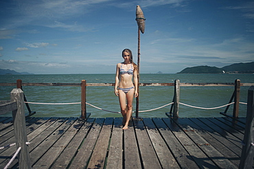 Caucasian woman wearing bikini standing on dock