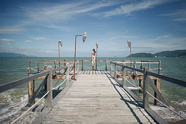 Caucasian woman wearing bikini standing on railing on dock