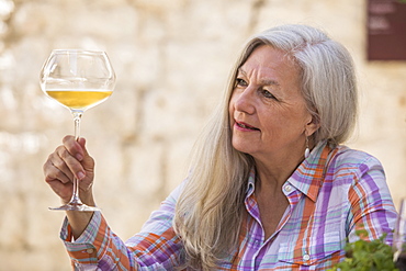 Older Caucasian woman examining white wine