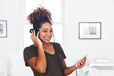 Mixed race woman listening to cell phone with headphones