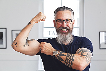 Close up of smiling muscular Caucasian hipster man flexing biceps