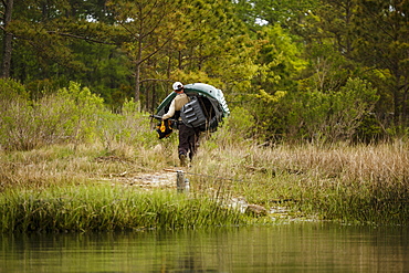 Caucasian man carrying fishing rod and kayak