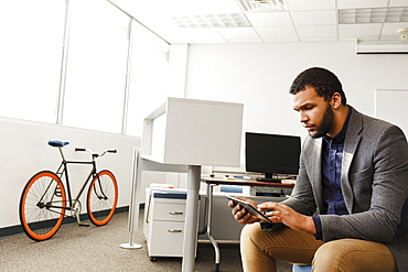 Mixed Race man using digital tablet in office