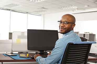 Smiling African American man using computer in office