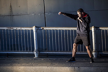 Caucasian man shadow boxing near railing