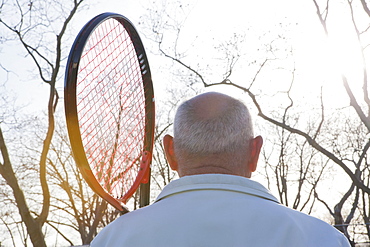 Rear view of Hispanic man holding tennis racket