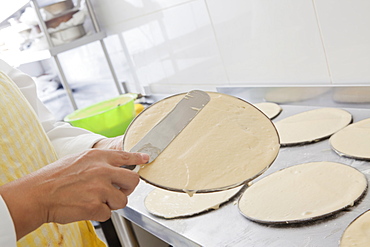 Hispanic woman spreading batter on pan