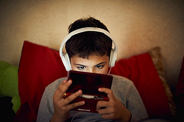 Hispanic boy listening to cell phone with headphones