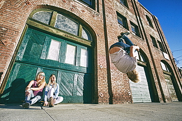 Woman watching man skateboarding on urban sidewalk