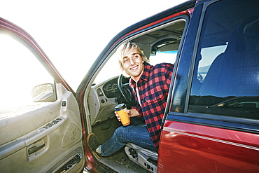 Caucasian man sitting in cat holding coffee cup