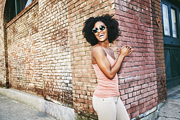 Laughing Black woman standing near corner of brick building