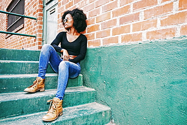 Black woman sitting on staircase outdoors