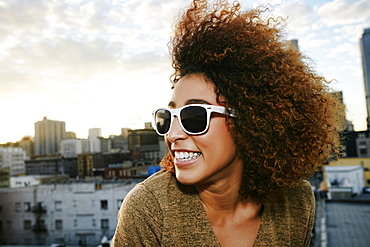 Portrait of smiling Hispanic woman on urban rooftop at sunset