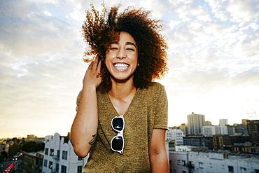 Portrait of smiling Hispanic woman on urban rooftop at sunset