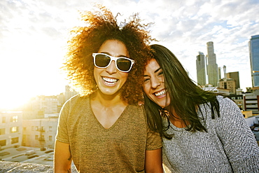 Portrait of smiling Hispanic women on urban rooftop at sunset