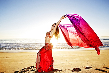 Caucasian belly dancer holding scarf on beach