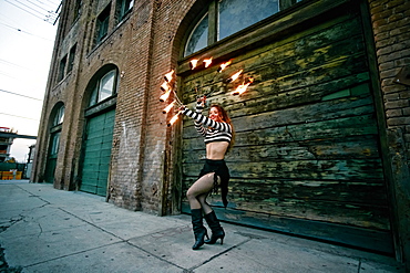 Caucasian woman juggling fire on city sidewalk