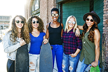 Women posing with skateboards in city