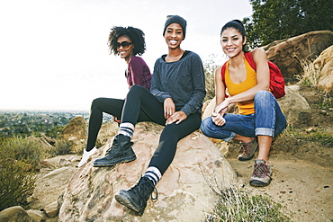 Portrait of smiling women sitting on rock