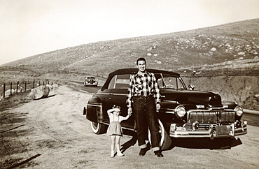 Portrait of Caucasian father and daughter posing near vintage car