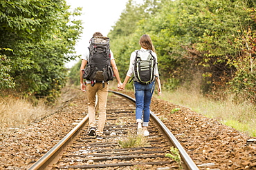 Caucasian couple walking on train tracks