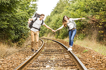 Caucasian couple balancing on train tracks