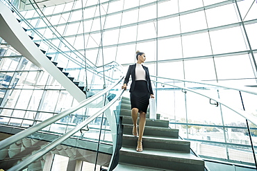 Pensive Mixed Race businesswoman descending staircase