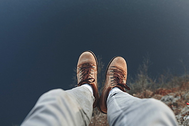 Legs of Caucasian man sitting at the edge of reservoir