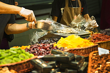 Worker scooping nuts into plastic bag at market