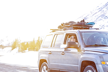 Friends driving in car with snowboards in winter