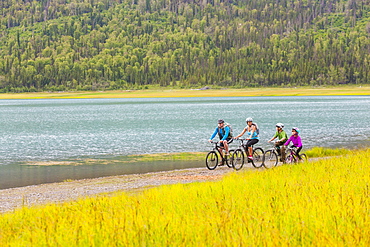 Couple with son and daughter riding bicycles near lake