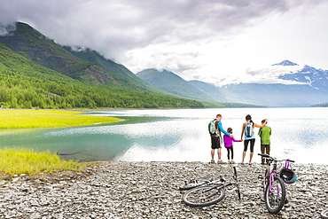 Couple with son and daughter riding bicycles near lake