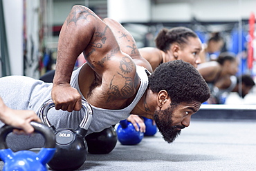 Man and women doing push-ups with kettlebells