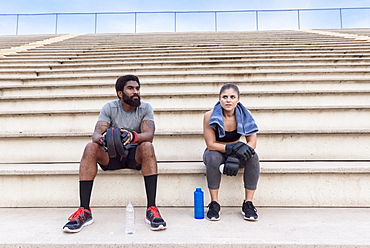 Trainer and woman resting on bleachers