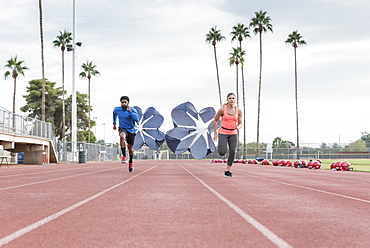 Man and woman running with parachutes on track