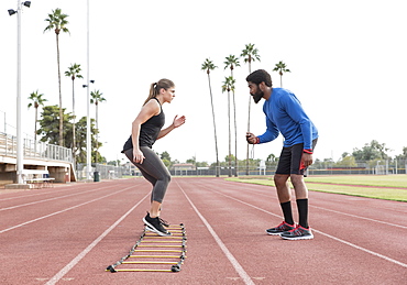 Trainer watching woman running ladder