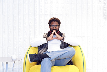 Pensive black man sitting in yellow chair