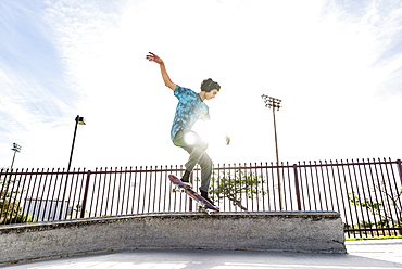 Hispanic man riding skateboard in skate park