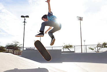 Hispanic man performing mid-air trick on skateboard