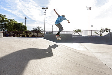 Hispanic man performing mid-air trick on skateboard