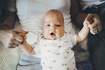 Caucasian mother holding hands of baby son in lap