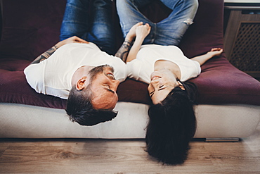 Caucasian couple laying upside-down on sofa