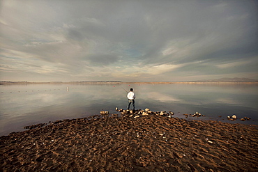 Distant man fishing on beach